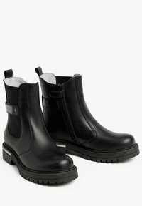 Stivali ankle neri in pelle liscia, con pannelli laterali elasticizzati, zip laterale e suola robusta con un leggero tacco.