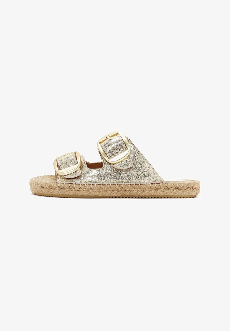 Goldfarbene Metallic-Espadrille mit zwei übergroßen Schnallen, geflochtener Jutesohle und flachem Profil. Glatte Textur mit glänzendem Finish.