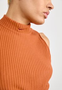 Ριγέ καμισάκι σε καμένο πορτοκαλί με ψηλό λαιμό και κεντημένο λογότυπο. Διαθέτει εφαρμοστή γραμμή και χωρίς μανίκια.