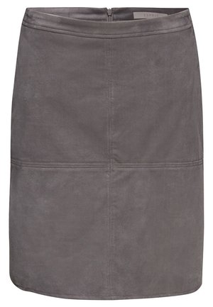 Femme portant un pull à col roulé bordeaux à manches longues, une jupe en daim grise et des bottes noires montant jusqu'aux genoux, debout devant un fond uni.
