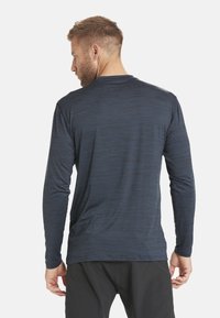 Herren Langarmhemd in Marineblau mit einem strukturierten, melierten Muster; verfügt über einen Rundhalsausschnitt und eine lockere Passform; das Material erscheint leicht und atmungsaktiv.
