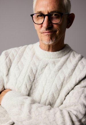 Weißer Kabelstrickpullover mit strukturiertem Muster, ausgestattet mit einem gerippten Rundhalsausschnitt und langen Ärmeln, getragen von einer Person mit grauem Haar.
