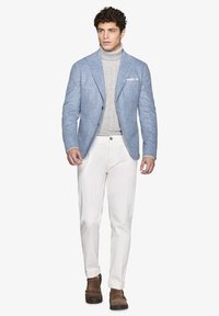 Blazer texturizzato azzurro chiaro, dolcevita grigio a coste, pantaloni bianchi e calzature marroni. Il blazer presenta due bottoni e un fazzoletto da taschino.