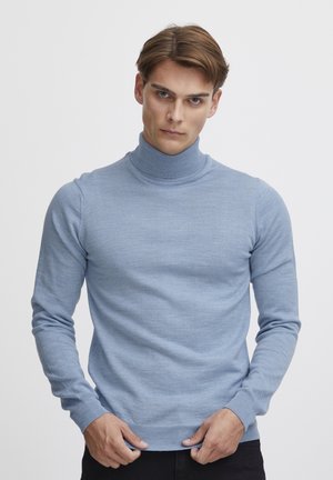 Helles blauer Rollkragenpullover, Strickstoff, lange Ärmel, taillierte Passform, subtiles Muster, gerippter Kragen und Saum. Kombiniert mit dunklen Hosen.
