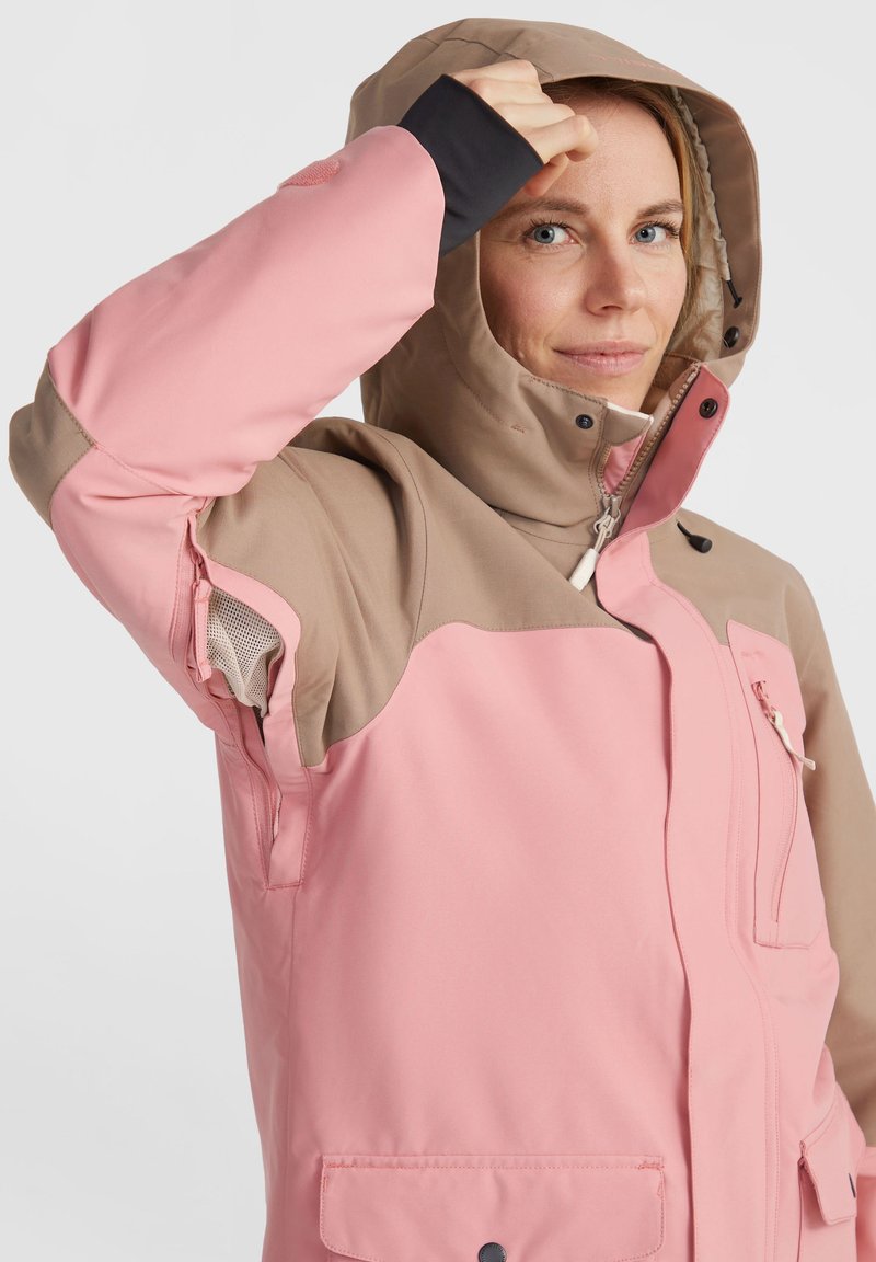 Roze en tan jas met een capuchon. Voorzien van een ritssluiting aan de voorkant, zijzakken en een mesh voering. De stof lijkt glad en lichtglanzend.