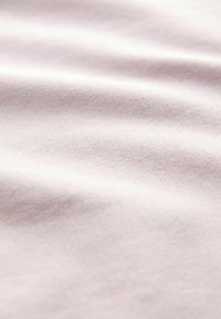 Tissu doux et de couleur claire avec des plis délicats et une texture lisse, présenté en gros plan.