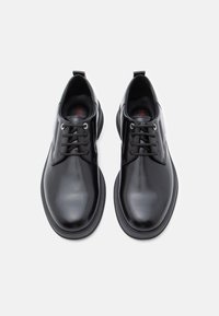 Zwarte leren schoenen met een gladde afwerking, veterontwerp en afgeronde neus. Voorzien van zwarte zolen en een minimalistische uitstraling.