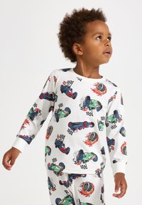 Baumwollpyjamas mit Rennwagen-Motiven in Rot, Grün und Schwarz auf einem weißen Hintergrund. Lange Ärmel und passendes Hosen-Design.