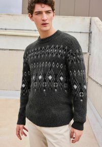 Dark gray knitted sweater featuring a geometric pattern in white and black. The design includes diamonds and accents in varying textures.