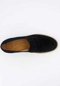 Mocassino in suede nero con cuciture decorative, punta tonda e soletta in pelle color tan; presenta una suola di un marrone chiaro a contrasto.