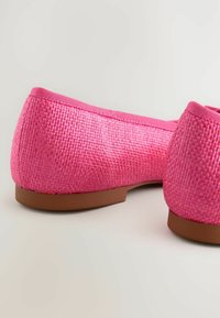 Leuchtend pinke Ballerinas mit einer gewebten Textur. Rund geschlossener Rücken mit einer glatten braunen Sohle und einer passenden pinken Akzentuierung am Öffnungsrand.