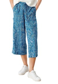 Sinisillä kuviollisilla lyhyillä housuilla, joissa on joustava vyötärönauha ja trooppiset lehtikuvioinnit, kevyt kangas. Yhdistetty valkoisiin tennareihin.