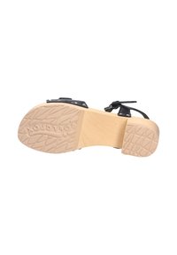 Schwarze Sandale mit einer strukturierten Sohle, ausgestattet mit einem hellen Holzabsatz. Verstellbarer Riemen mit kleinen Nieten für den Detailakzent.