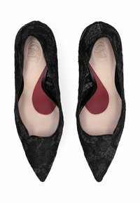 Paire de ballerines noires en dentelle à bouts pointus avec semelles intérieures beiges et insert de soutien de la voûte plantaire bordeaux, vues de dessus sur fond blanc.