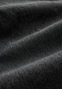 Tummanharmaa kangas, jossa on hieno viistokudonta ja pehmeitä poimuja, jotka luovat valon ja varjon kontrasteja.