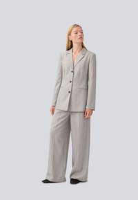 Grey striped suit featuring a tailored blazer with notched lapels, single-breasted, and wide-leg trousers for a modern, structured silhouette.
