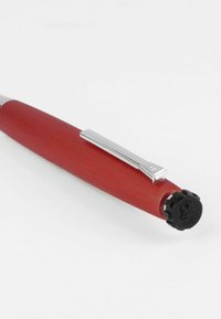 Red cylindrical pen with a matte finish, silver clip, and a textured black cap featuring a logo. Sleek design with smooth edges.
