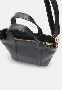 Black leather handbag with a textured finish, dual top handles, and an adjustable strap. Features a zippered main compartment with gold hardware.