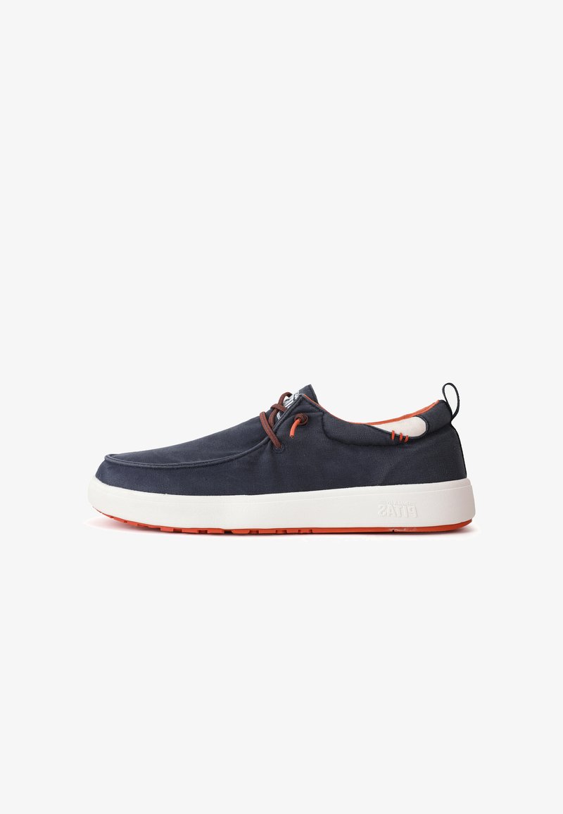 Marineblauwe canvas schoen met een witte tussenzool en oranje outsole. Heeft bruine veters en stikseldetails. Rond de teen met een instapontwerp.