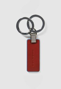 Rode leren sleutelhanger met blauwe randen, voorzien van metalen beslag en twee chromen sleutelhangers bevestigd met een zilveren sluiting.