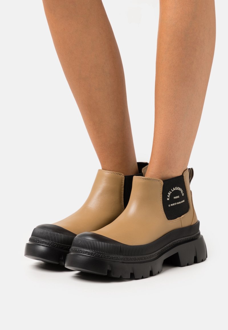 Stivali alla caviglia in pelle color cuoio con suola in gomma nera, pannelli laterali elasticizzati e marchio ben visibile su una linguetta posteriore. Design della suola chunky e con battistrada.