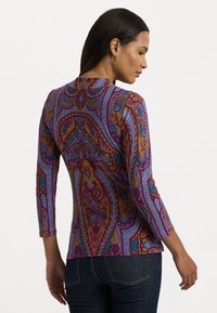 Trijų ketvirčių rankovių palaidinė, pasižyminti ryškiu purpuro spalvos ir paisley raštu, pagaminta iš lygaus audinio su smulkia tekstūra ir detalėmis.