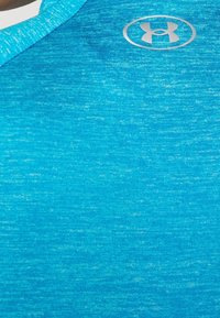 Tyrkysové sportovní tričko s texturovanou látkou, kulatým výstřihem a stříbrným logem na prsou.