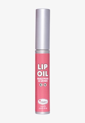 Lip oil met een roze tube en een zilveren dop. Bevat vetgedrukte witte tekst. Inhoud: 7 mL. Het label vermeldt "the Balm," wat het merk van het product aanduidt.