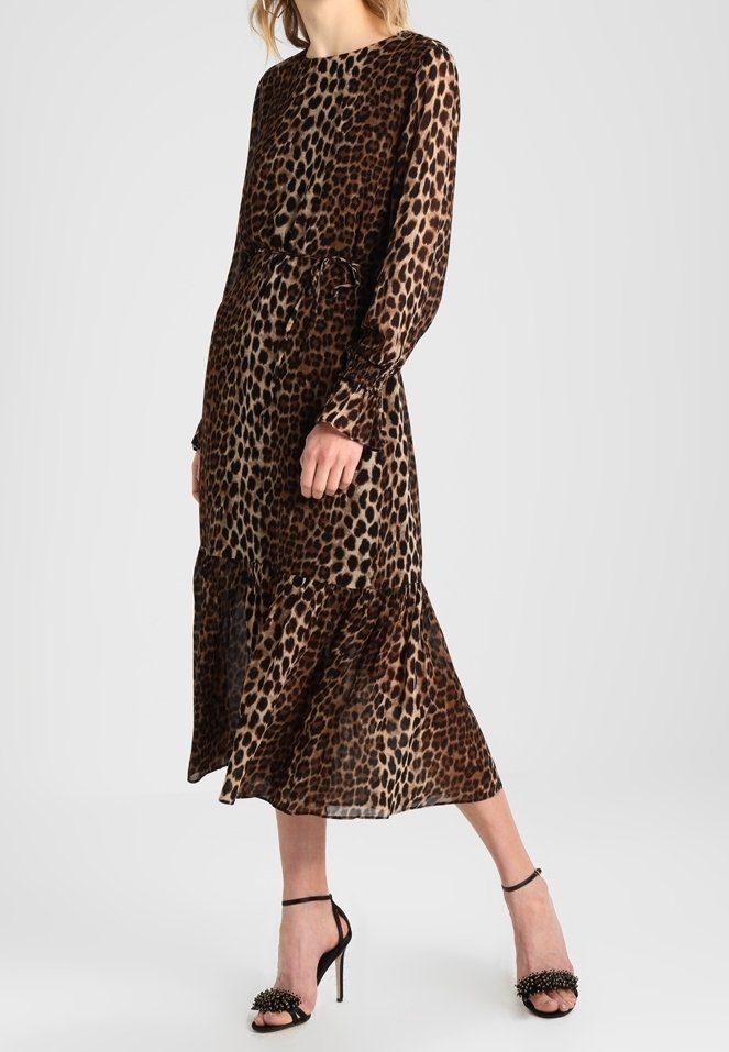 Klänning med leopardmönster, långa ärmar, insvängd midja och lagerpåsatt kjol. Genomskinligt tyg och en flödande silhuett, parat med svarta remsandaler.