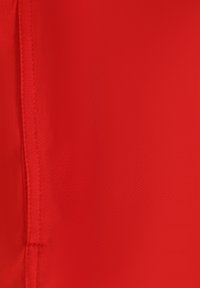 Roter Stoff mit einer glatten, leicht strukturierten Oberfläche und sichtbaren Nahtdetails. Die Farbe ist lebhaft und gleichmäßig über das Material verteilt.