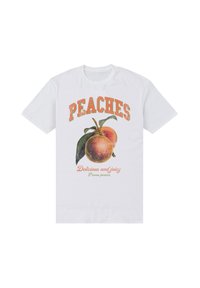 Vit t-shirt med grafik av två persikor och gröna blad, texten "PEACHES" i stora orangea bokstäver, "Läckra och saftiga" nedan i kursiv.