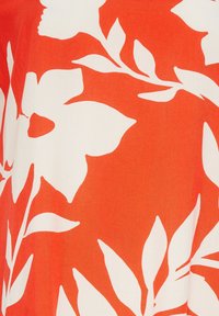 Tissu rouge avec un grand motif floral blanc et des feuilles vertes. La texture semble lisse, avec une qualité légère et respirante.