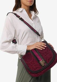 Borsa a tracolla in suede bordeaux con design floreale in rilievo, un clasp dorato e una tracolla regolabile a strisce in rosa scuro e chiaro.