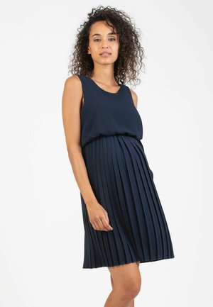Navy blue maternity dress with a fitted top and pleated skirt. Made from soft fabric, featuring a round neckline and sleeveless design.