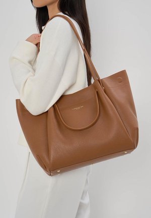 Sac fourre-tout en cuir texturé marron avec une forme arrondie, double poignée, poche frontale proéminente et détails en métal doré.