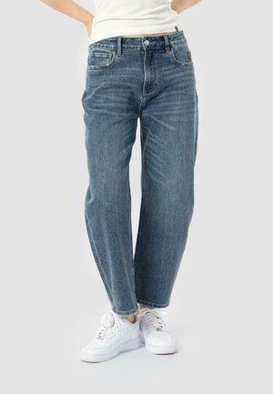 Jeans in jeans blu chiaro con taglio dritto, caratterizzati da tasche frontali, un sottile motivo a macchie e orli rifiniti, indossati con sneakers bianche.