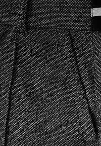 Teksturowana czarna tkanina z wzorem w kratkę, charakteryzująca się gładkim wykończeniem. Zawiera kontrastowe szwy oraz poziome paski.