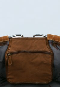 Bruine stoffen tas met een ritsvak, zilverkleurige hardware en stikseldetails. Interieur heeft een gestructureerde grijze voering met een subtiel patroon.