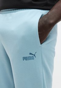 Ανοιχτό μπλε παντελόνια τζόγκινγκ από μαλακό ύφασμα, με πλαϊνή τσέπη και κεντημένο λογότυπο Puma σε πιο σκούρο μπλε χρώμα στο μηρό.