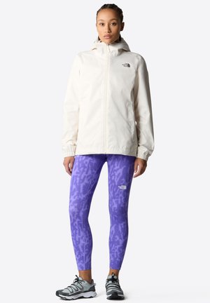 White waterproof jacket with a hood, paired with purple patterned leggings. The look is completed with gray athletic shoes.