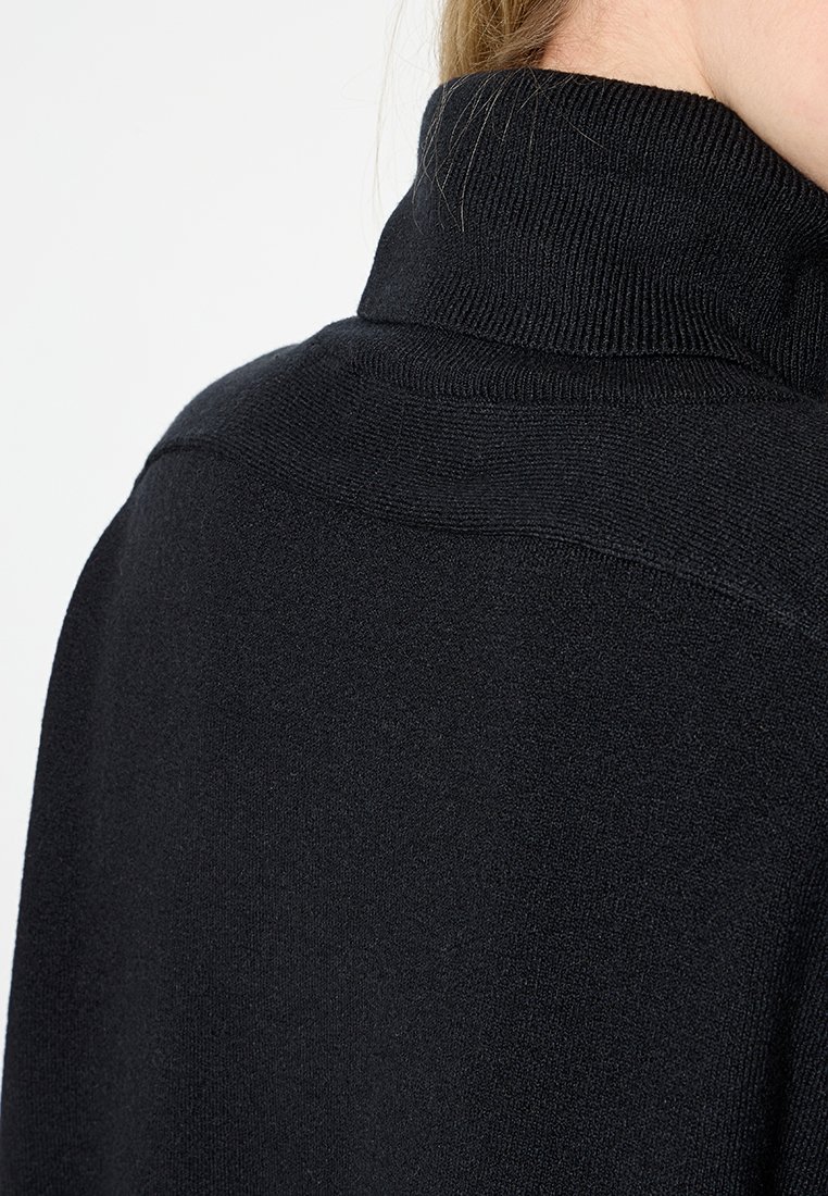 Czarny sweter z dzianiny z wysokim kołnierzem, z prążkowanym kołnierzem i gładką teksturą, widziany z tyłu, podkreślający materiał i dopasowanie.
