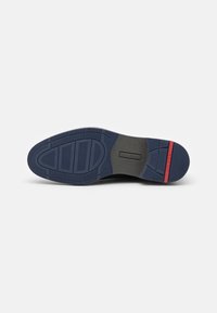 Schuhsohle aus strukturiertem, marineblauem Gummi mit schwarzem Grund, rotem Akzent und gemustertem Profil für besseren Halt.