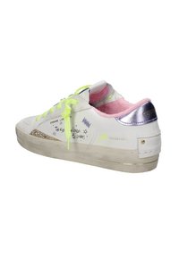 Sneaker bianco con lacci verde neon, fodera rosa, accenti metallici argentati e testo decorativo. Presenta un tallone argentato texture e dettagli glitter.