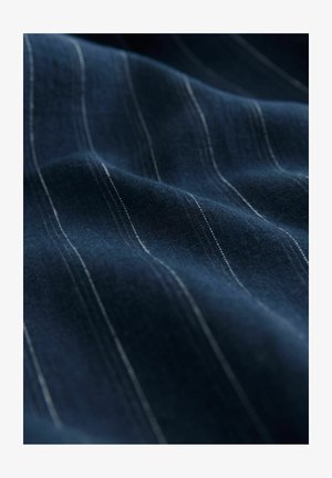 Tessuto blu navy con sottili strisce verticali bianche, che mostra una texture liscia e una leggera lucentezza, piegato per enfatizzarne il drappeggio e la morbidezza.