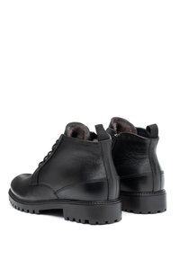 Czarne skórzane botki za kostkę z teksturowanym wykończeniem, sznurowanym przodem i pętlami do zakładania. Grube, gumowe podeszwy z głębokim bieżnikiem zapewniające przyczepność i trwałość.
