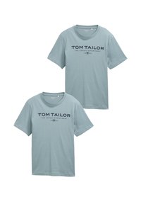 Zwei hellblaue Baumwoll-T-Shirts, die zusammen ausgestellt sind. Jedes hat kurze Ärmel und einen Rundhalsausschnitt, mit einem marineblauen Logo auf der Vorderseite.