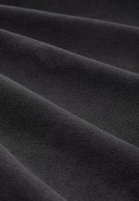 Czarna tkanina pleciona o gładkiej fakturze, ukazująca wyraźne fałdy i matowe wykończenie. Jednolity kolor bez widocznych wzorów ani akcentów.