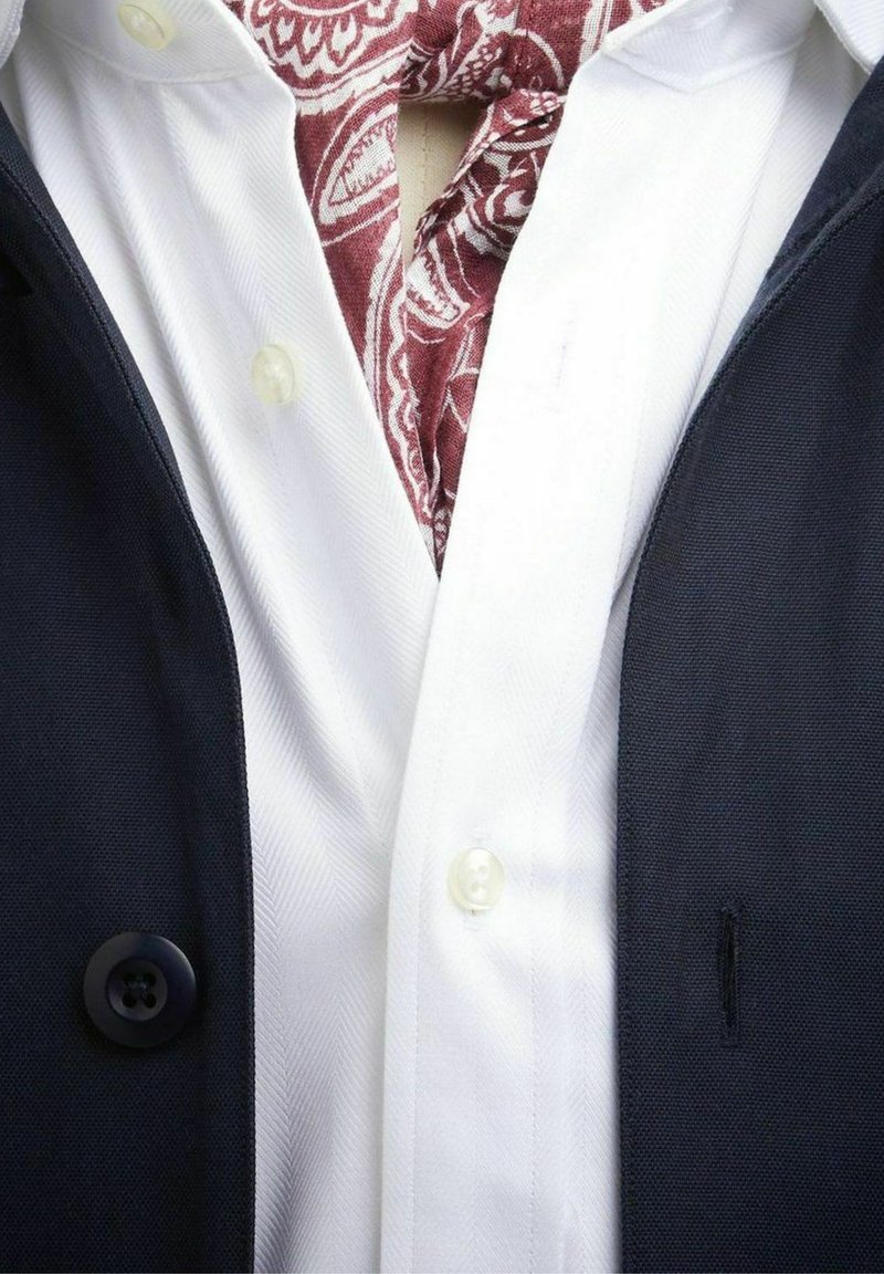Marineblazer i et struktureret stof, en hvid skjorte med hælderibåndsmønster og et bordeaux paisley lommefyr.