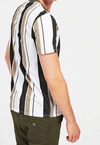Camiseta de hombre de manga corta con rayas verticales en negro, blanco y verde oliva. Material de algodón, cuello redondo, diseño ajustado, con costuras decorativas.
