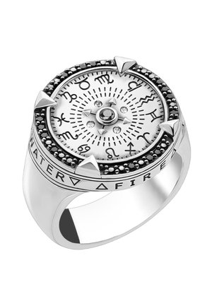 Silberner Ring mit Sternzeichen um ein weißes rundes Zifferblatt, schwarzer Stein in der Mitte, vier dreieckigen Markierungen und Elementsymbolen am Ringband.